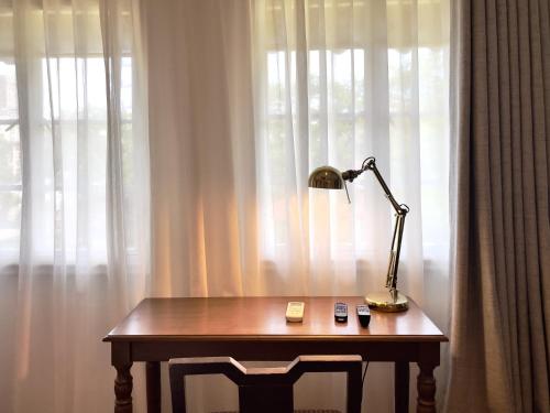 a lamp sitting on a wooden table in front of a window at MiraNamin Nest LIRYO and LANTANA Residence in Unique Historic Home - Garden, Rooftop, Private Kitchen in Manila