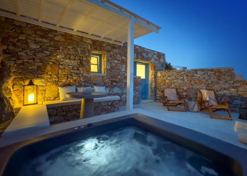 a hot tub on a patio with a stone wall at Garbis in Karavostasi