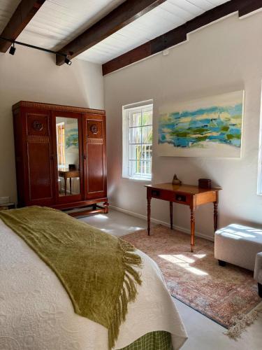 Un dormitorio con una cama, una mesa y un escritorio. en Sevilo Farmhouse, en Stellenbosch