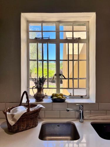 Una encimera de cocina con un fregadero y una ventana. en Sevilo Farmhouse, en Stellenbosch