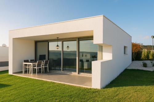 Casa blanca con mesa y sillas en el césped en Carina Villas, en Lourinhã