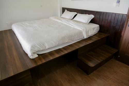 a bed with white sheets and pillows on a wooden platform at Michelia Valley Hotel in Da Lat