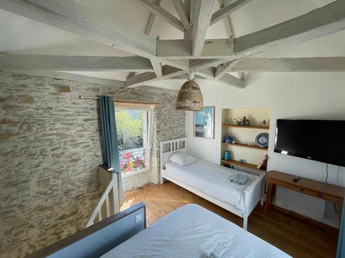 un salon avec une télévision et un mur en pierre dans l'établissement Logement entier - Le pigeonnier de la plume, à Nantes