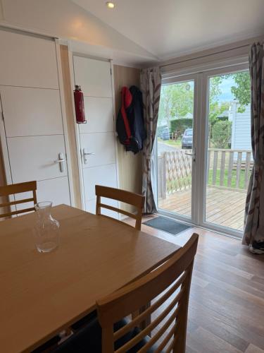 d'une salle à manger avec une table et une porte coulissante en verre. dans l'établissement Mobile home les sablines, à Vendres-Plage