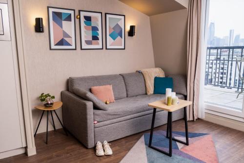 a living room with a couch and a window at Aparthotel Adagio Paris Suresnes Longchamp in Suresnes