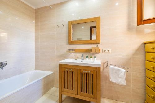 une salle de bain avec un lavabo, une baignoire et un miroir dans l'établissement Porto Cristo 6 persons, à Manacor