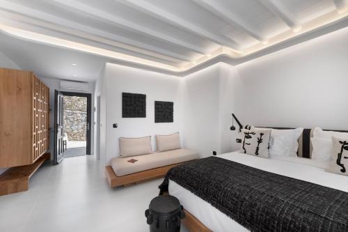 a white bedroom with a bed and a couch at Deliades Hotel in Ornos