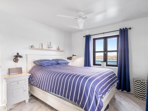 a bedroom with a bed and a window with blue curtains at Ocean Mist in Carna