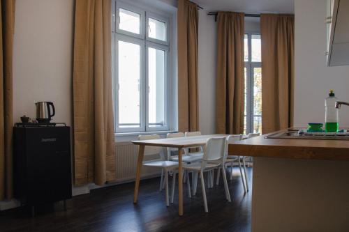 a kitchen with a table and chairs and windows at Arbio I Apartmently Studios & Apartments in Berlin