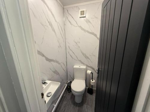 a small bathroom with a toilet and a sink at Stunning 4-Bed House in Bridgend in Bridgend