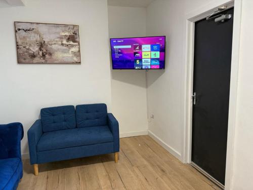 a room with a blue chair and a tv on a wall at Stunning 4-Bed House in Bridgend in Bridgend