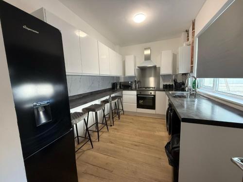 a kitchen with a black refrigerator and some bar stools at Stunning 4-Bed House in Bridgend in Bridgend