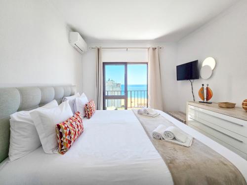 a bedroom with a large white bed with a large window at Apartments Edifício Cruzeiro in Portimão