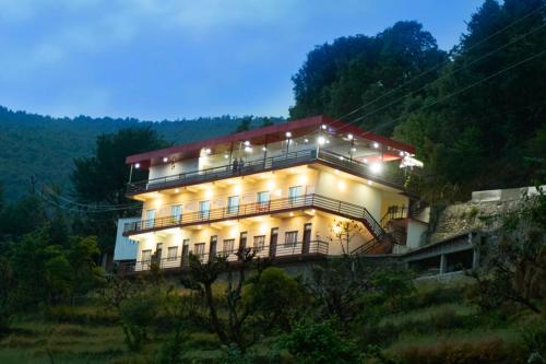a building on a hill with lights on at LA Riqueza Sushanti Retreat - Mountain View Rooms with Balcony # Pure Veg Restaurant # Jain Food Available # Parking # Customer's choice Hotel in Gupta Kāshi
