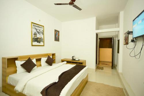 a bedroom with a bed and a flat screen tv at LA Riqueza Sushanti Retreat - Mountain View Rooms with Balcony # Pure Veg Restaurant # Jain Food Available # Parking # Customer's choice Hotel in Gupta Kāshi