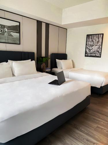 two beds in a hotel room with a laptop on top at 12 The Residence Hotel at Don Mueang Airport in Bangkok