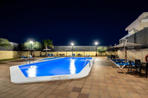 a swimming pool at night with chairs and umbrellas at Hospedium Hotel Abril in San Juan de Alicante