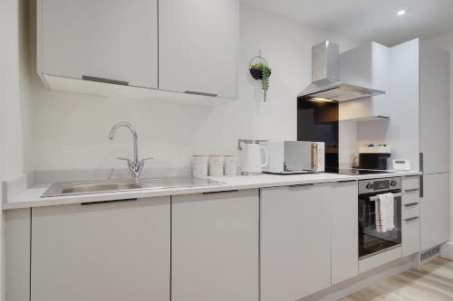 a white kitchen with white cabinets and a sink at Wimborne Road Apartment 4 in Bournemouth