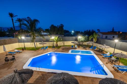 a swimming pool at night with umbrellas and chairs at Hospedium Hotel Abril in San Juan de Alicante