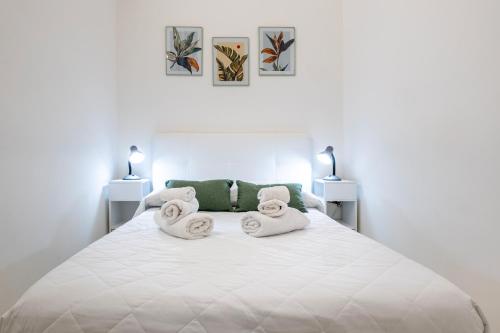a white bedroom with a large white bed with towels at Dimora Biscari in Acate