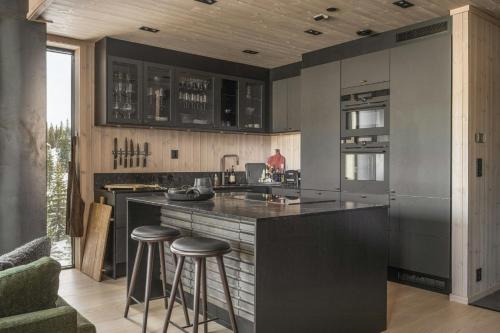 a kitchen with a large island with bar stools at Modern Top Floor Apartment By Kvitfjell Ski Resort in Favang