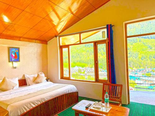 a bedroom with a bed and a table and windows at Hotel The Premium Villa Manali View in Manāli