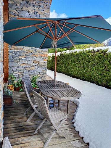 une table en bois et deux chaises avec un parasol dans l'établissement Chalet Spacieux à Chamonix pour 9 – Vue Panoramique Mont-Blanc, Jacuzzi, Jardin & Parking, à Chamonix-Mont-Blanc