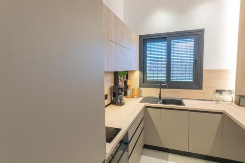 a kitchen with white cabinets and a window at Serein Houses -No1- in Gargaliánoi
