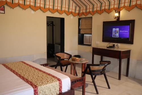 a bedroom with a bed and a desk and a television at Jawai Bera Leopard Camp in Bera