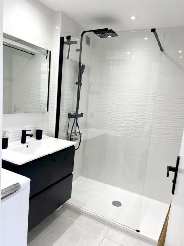 une salle de bain blanche avec une douche et un lavabo dans l'établissement 3 pièces au centre de Juan les Pins, à Juan-les-Pins