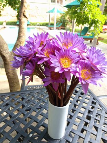 a white vase filled with purple flowers on a table at Villa Rumassala Luxury Chalets Unawatuna in Unawatuna