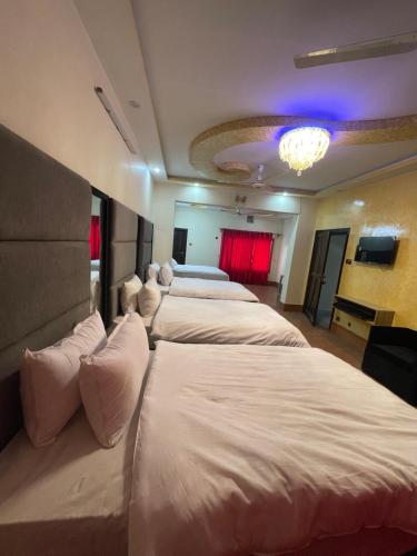 a row of four beds in a hotel room at Aban Suites in Dargai