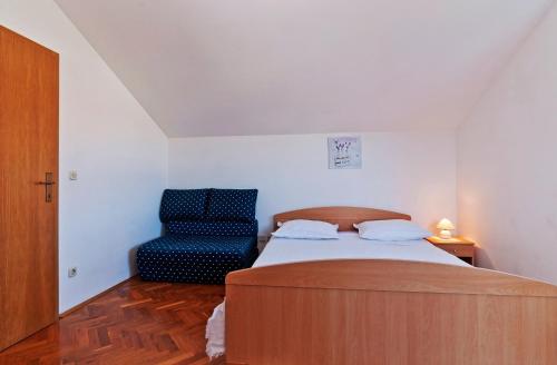 - une chambre avec un lit et une chaise bleue dans l'établissement Apartments Bruno, à Petrčane