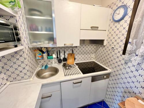 une petite cuisine avec un évier et une horloge murale dans l'établissement 3P Bright in Palm Beach, à Cannes