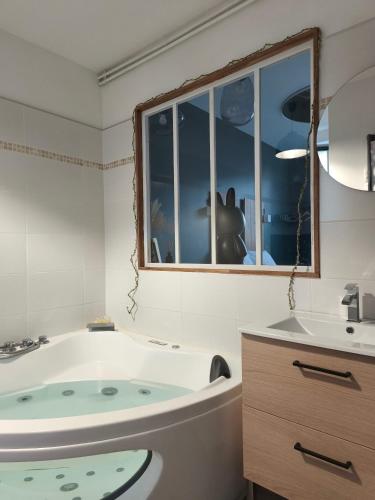 une salle de bain avec une baignoire, un lavabo et une fenêtre dans l'établissement La Rêverie, à Rezé
