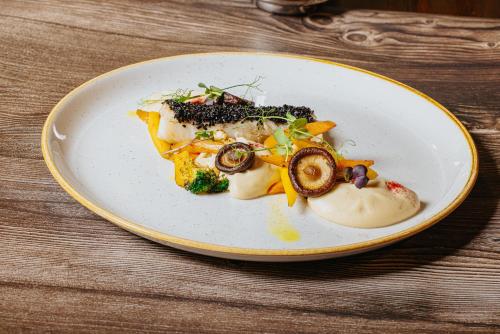 a white plate with food on a wooden table at Penzion Drak in Liptovský Mikuláš
