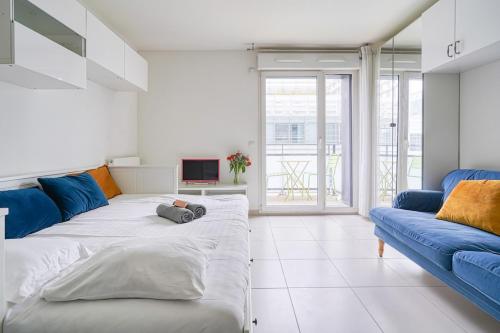 Cette chambre comprend un grand lit et un canapé bleu. dans l'établissement À deux pas de Paris - Le Confidentiel - 8MB, à Issy-les-Moulineaux