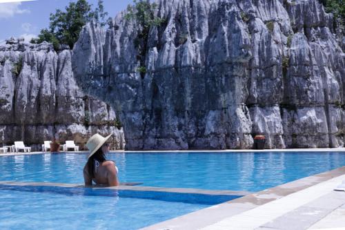 a woman in a hat sitting in a swimming pool at Wood Hills Hotel & Resort in Mayrūbā