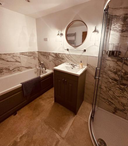 a bathroom with a sink and a shower with a mirror at The Forge, Newly Converted Barn in Carnforth