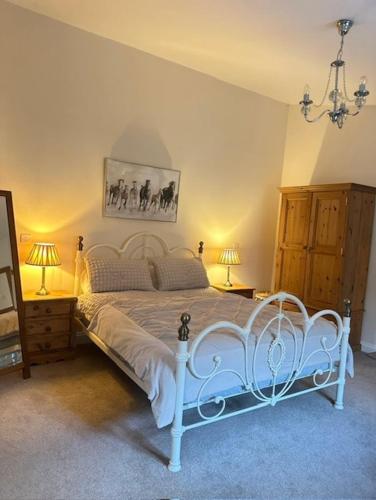 a bedroom with a white bed with two lamps and a mirror at The Forge, Newly Converted Barn in Carnforth