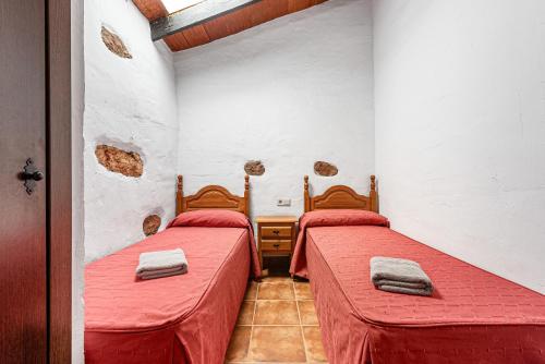two beds in a room with red sheets at El Pajar in Málaga