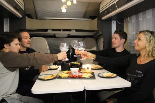 un groupe de personnes assises autour d'une table avec des verres à vin dans l'établissement CAMPING-CAR TOURISTIQUE du JURA, à Dole