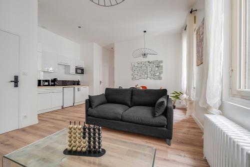 un salon avec un canapé noir et une table dans l'établissement Appartement lumineux avec salle de sport, Centre, à Saint-Étienne