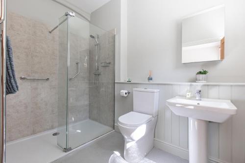 a bathroom with a shower and a toilet and a sink at Stylish Coach House Retreat in Wymondham