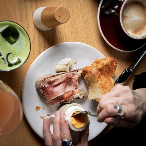 a plate with a sandwich and an egg on a table at Greulich Design & Boutique Hotel in Zürich