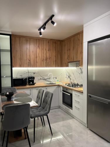 a kitchen with a table and a stainless steel refrigerator at Wood Нова затишна 2-кімнатна квартира in Ternopilʼ