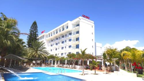 a hotel with a swimming pool in front of a building at Corfu Hotel in Ayia Napa