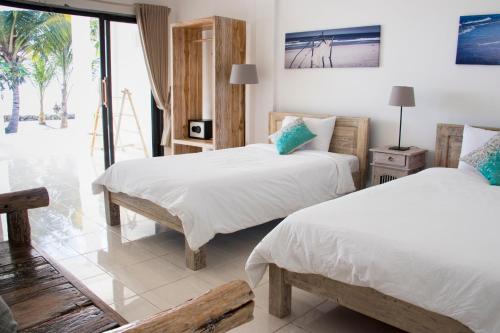 two beds in a room with a view of the ocean at Myamo Beach Lodge in Jereweh