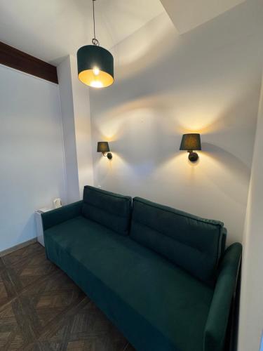 a green couch in a living room with two lights at Bieszczadzki Dworek Polanczyk in Polańczyk