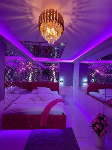 a purple bedroom with a bed and a chandelier at Apartament "Love Heaven" Jacuzzi SPA z dużą wanną z hydromasażem dla Dwojga in Gniezno